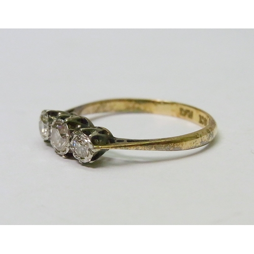 56 - A trilogy ring comprising three illusion set brilliant cut diamonds in a yellow metal setting marked... 