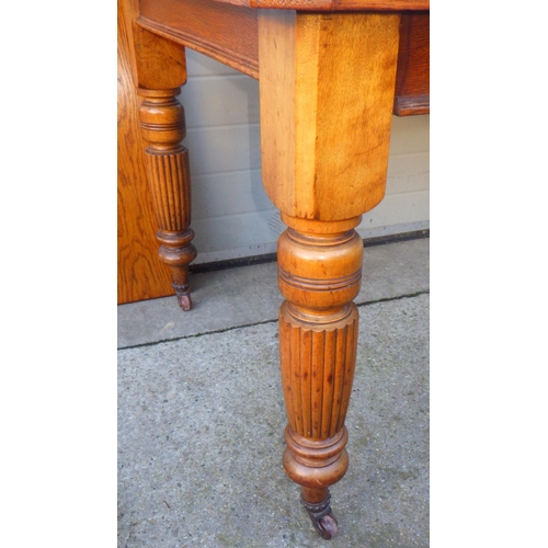 705 - An Edwardian oak wind out dining table with one leaf on reeded legs, together with a set of four Edw... 