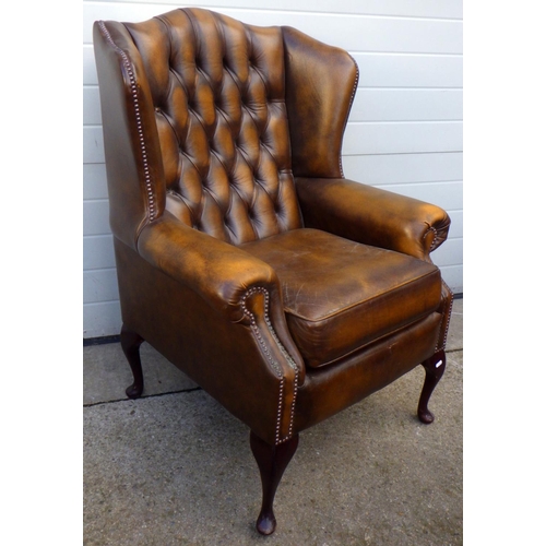 752 - A brown buttoned leather wingback armchair