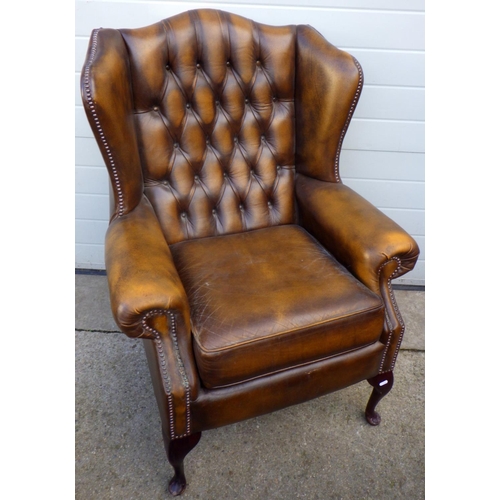 752 - A brown buttoned leather wingback armchair