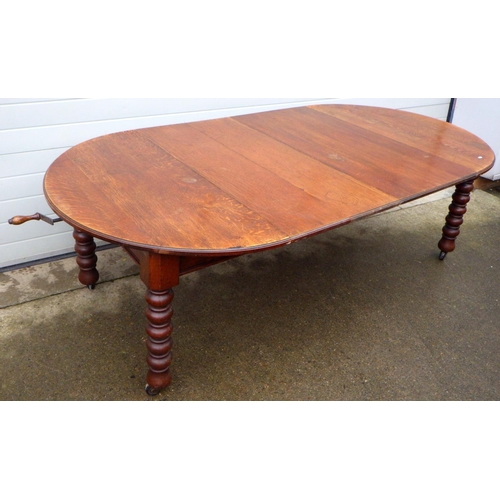 809 - A late Victorian oak wind out dining table with one and two half leaves on turned legs, approx 245cm... 