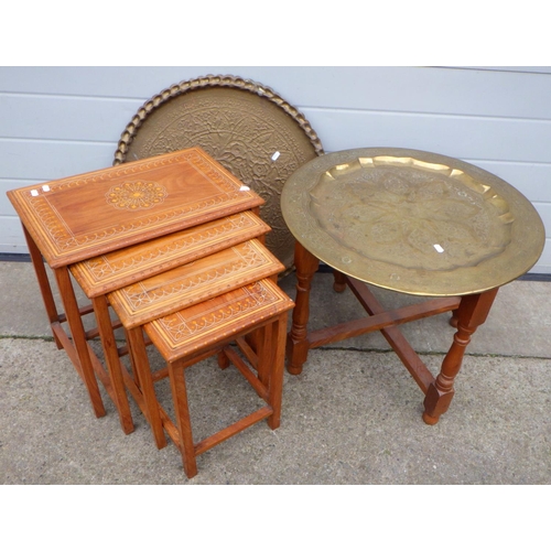 660 - A circular brass tray on stand, another brass tray and a nest of occasional tables (3)