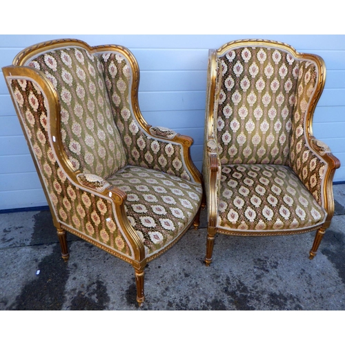 769 - A pair of giltwood wingback armchairs on turned & fluted legs, frames loose