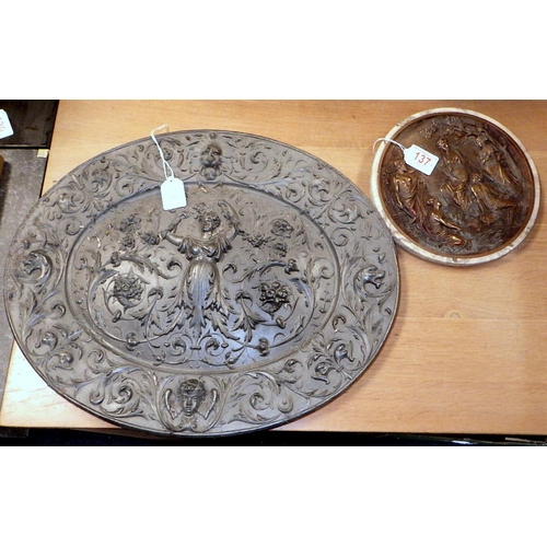137 - An oval heavy cast metal relief plaque together with a circular wall plaques (2)