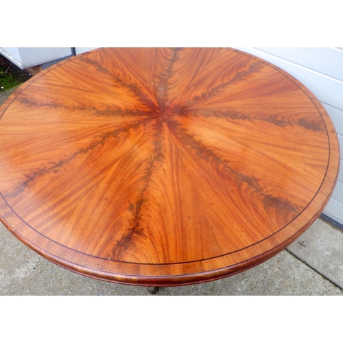 821 - A 19th cen mahogany breakfast table with sectioned top on turned and carved base with brass castors,... 