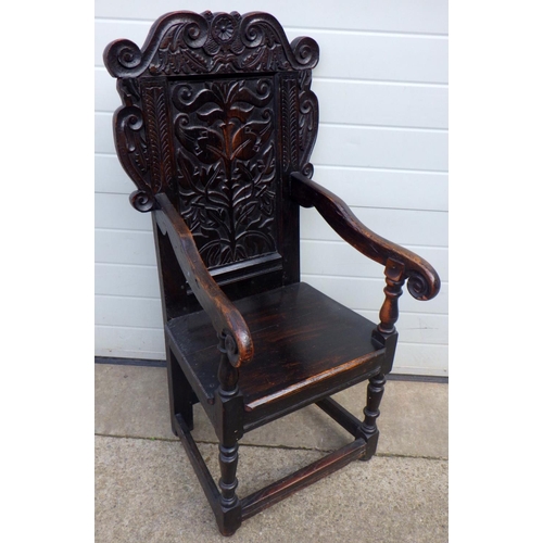 849 - A carved oak panel back chair, panel split, 116cm tall