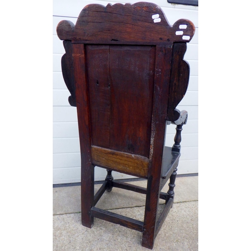 849 - A carved oak panel back chair, panel split, 116cm tall