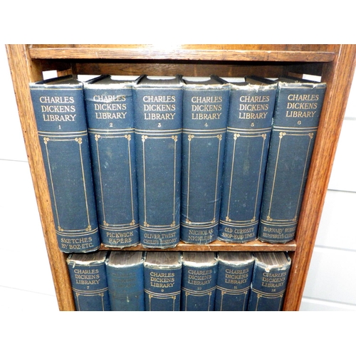 901 - A set of 18 Charles Dickens books within a narrow oak bookcase, 34cm wide