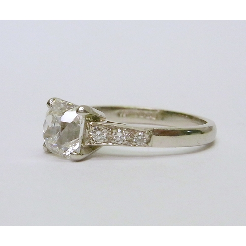 32 - A solitaire ring comprising an old cushion cut diamond with diamond shoulders in a platinum claw set... 