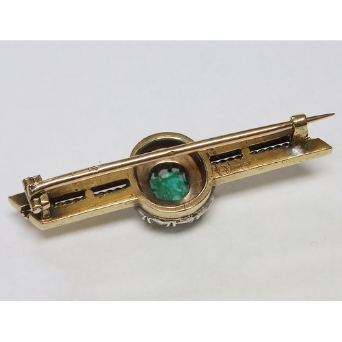 39 - A bar brooch, yellow and white metal set with a cluster comprising a central emerald surrounded by a... 