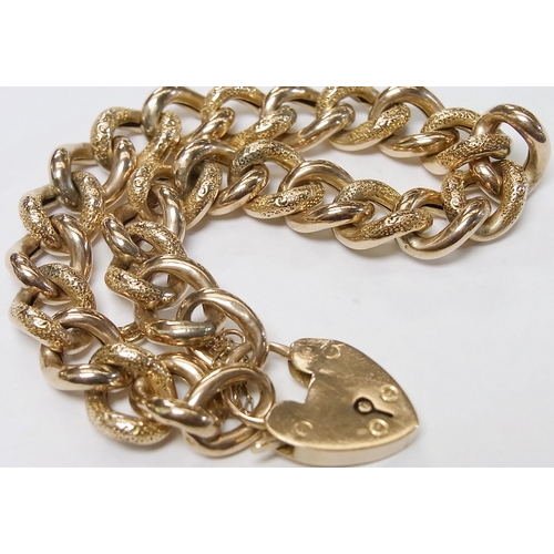 57 - A patterned curb bracelet fastening on a padlock clasp, yellow metal marked 9ct.  Approximately 180m... 