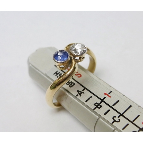 90 - A two stone twist ring set with a round cut diamond and a round cut sapphire, yellow metal marked 18... 