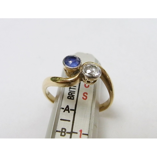 90 - A two stone twist ring set with a round cut diamond and a round cut sapphire, yellow metal marked 18... 