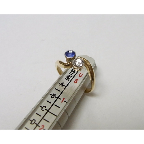 90 - A two stone twist ring set with a round cut diamond and a round cut sapphire, yellow metal marked 18... 