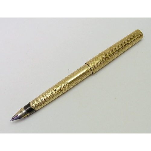 128 - A Parker 105 fountain pen having a gold plated bark-effect barrel and cap with a 14k white nib; a co... 