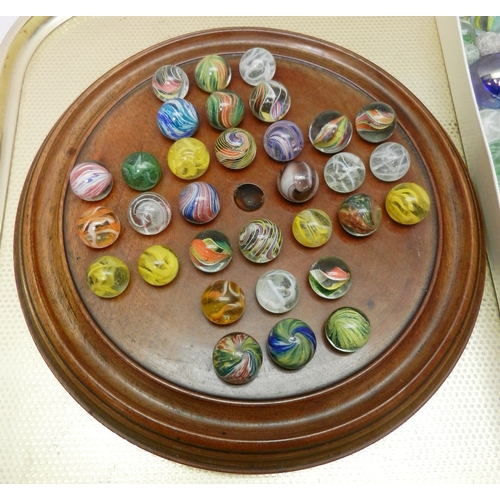 327 - A collection of  glass marbles together with a turned wood solitaire board.