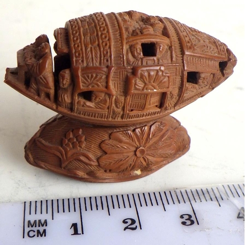 465 - A Chinese coquilla nut intricately carved as a junk with functioning doors, 40mm long.  Presented st... 