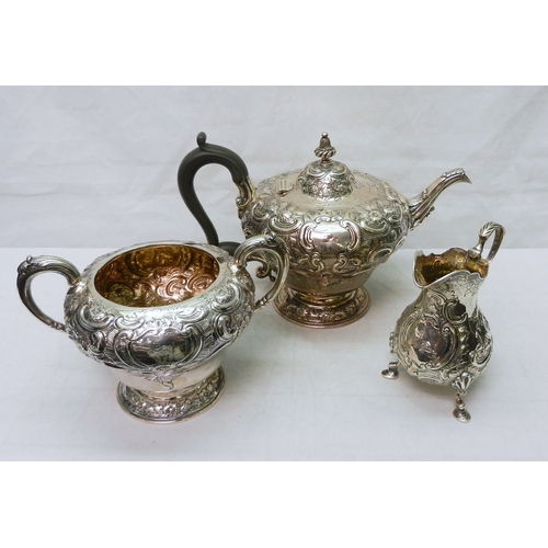 26 - A Victorian silver three piece repousse matched tea set comprising teapot, tripod milk jug, and suga... 