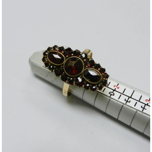 60 - A cluster ring, comprising an oval head set with mixed cut garnet stones in a yellow metal setting m... 