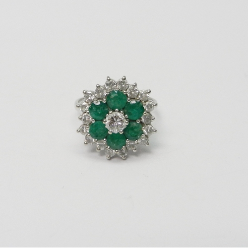 109 - A cluster ring comprising a central round cut diamond surrounded by a ring of six round cut emeralds... 