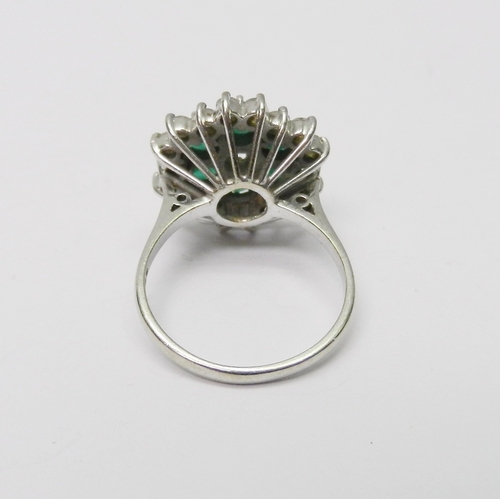 109 - A cluster ring comprising a central round cut diamond surrounded by a ring of six round cut emeralds... 