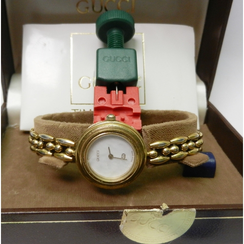 115 - A Gucci multi-bezel / change-bezel bangle watch, gold plated base metal together with 16 coloured be... 