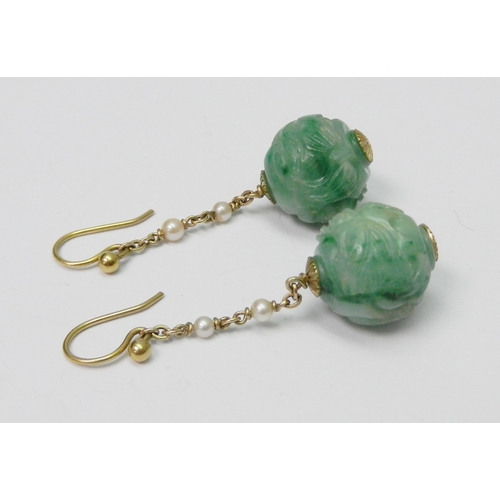 86 - A pair of jade bead droplet earrings each comprising a carved globular bead suspended on a yellow me... 