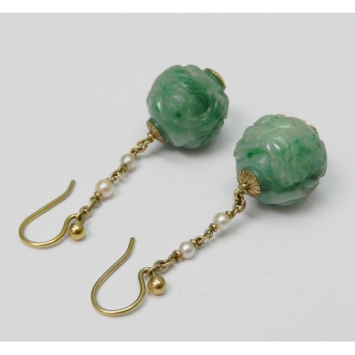 86 - A pair of jade bead droplet earrings each comprising a carved globular bead suspended on a yellow me... 
