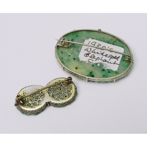 88 - A jade panel brooch on an unmarked white metal mount, the panel carved with a scene depicting an ele... 