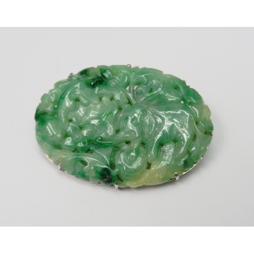 88 - A jade panel brooch on an unmarked white metal mount, the panel carved with a scene depicting an ele... 