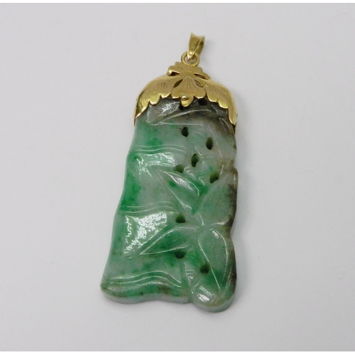 93 - A mottled jade pendant carved with a bamboo motif design, having an unmarked yellow metal 