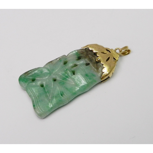 93 - A mottled jade pendant carved with a bamboo motif design, having an unmarked yellow metal 