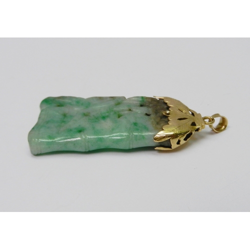 93 - A mottled jade pendant carved with a bamboo motif design, having an unmarked yellow metal 