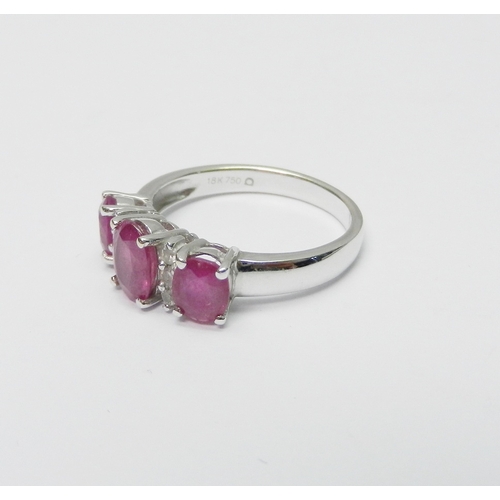 137 - A trilogy style ring comprising three graduated oval cut pink sapphires spaced with two pairs of rou... 