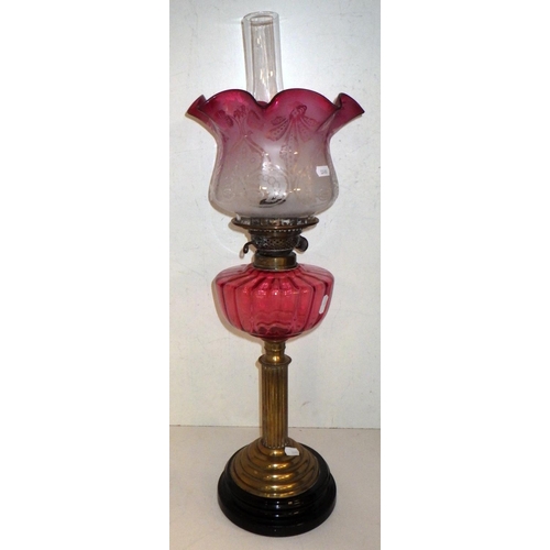 336 - An early 20thC oil lamp with cranberry shade