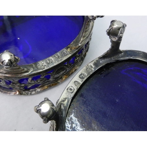 9 - A pair of George III silver and blue glass Rococo revival table salts standing on four claw feet, Da... 