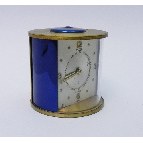 81 - A Jaeger desk / bedside alarm clock comprising an 8 day manual wind movement in a brass and blue ano... 