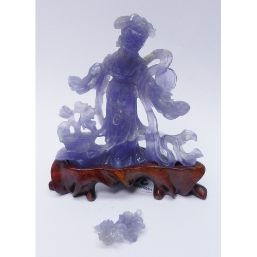 306 - A Chinese statuette depicting a female figure holding a fan and flowers, carving in purple hardstone... 