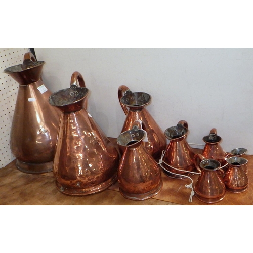 A group of nine graduated copper jugs