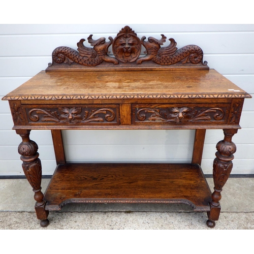 727 - A lion mask carved oak, two drawer side table, 108cm wide