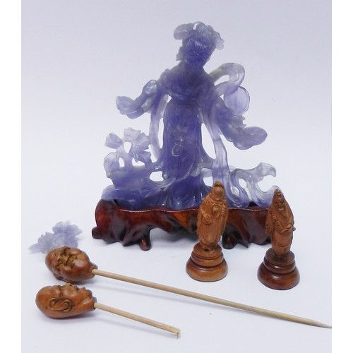 172 - A Chinese statuette depicting a female figure holding a fan and flowers, carving in purple hardstone... 