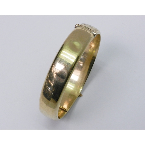 107 - A hinge bangle, 9ct gold late 20th cent.  A/F dented.  59mm interior diameter at hinge / 17g