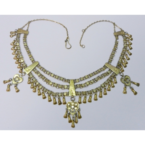 63 - A Middle Eastern triple chain fringe necklace, yellow metal indistinctly marked.  480mm long / 65mm ... 