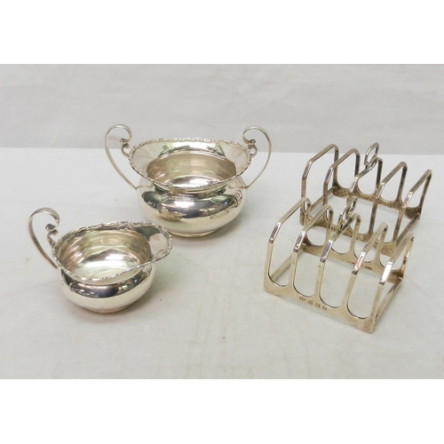 18 - A matching silver jug and two-handled sugar basin; a pair of silver toast racks.  Jug 85mm long incl... 