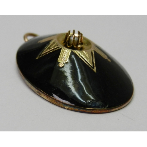 60 - An oval mourning pendant, black enamel on yellow metal having a central seed pearl in a claw setting... 