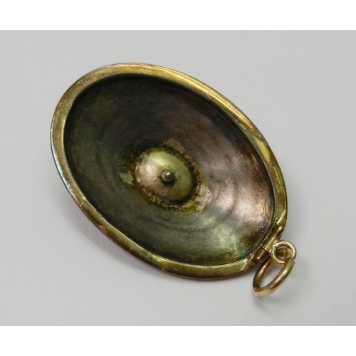 60 - An oval mourning pendant, black enamel on yellow metal having a central seed pearl in a claw setting... 