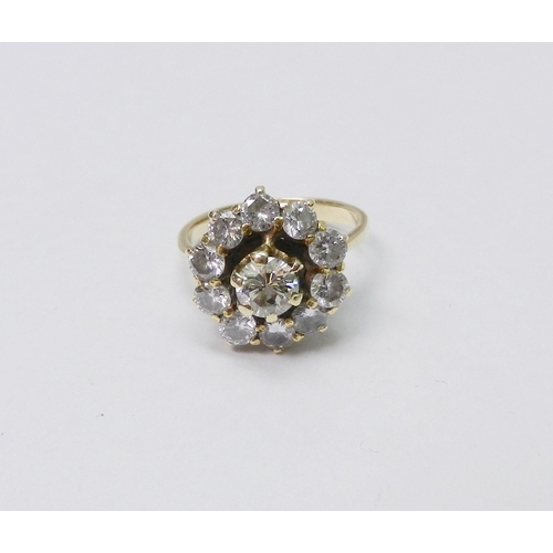 56 - A diamond cluster ring comprising a principal round cut stone in a raised claw setting surrounded by... 