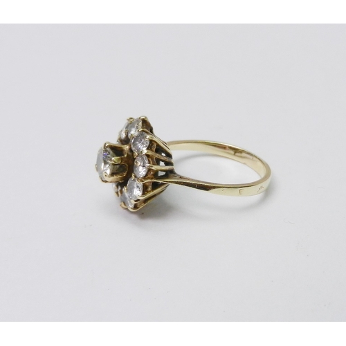 56 - A diamond cluster ring comprising a principal round cut stone in a raised claw setting surrounded by... 