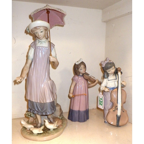 132 - A Lladro figure of a girl feeding birds 33cm tall together with two NAO figures, one missing bow, um... 