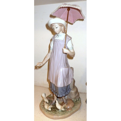 132 - A Lladro figure of a girl feeding birds 33cm tall together with two NAO figures, one missing bow, um... 